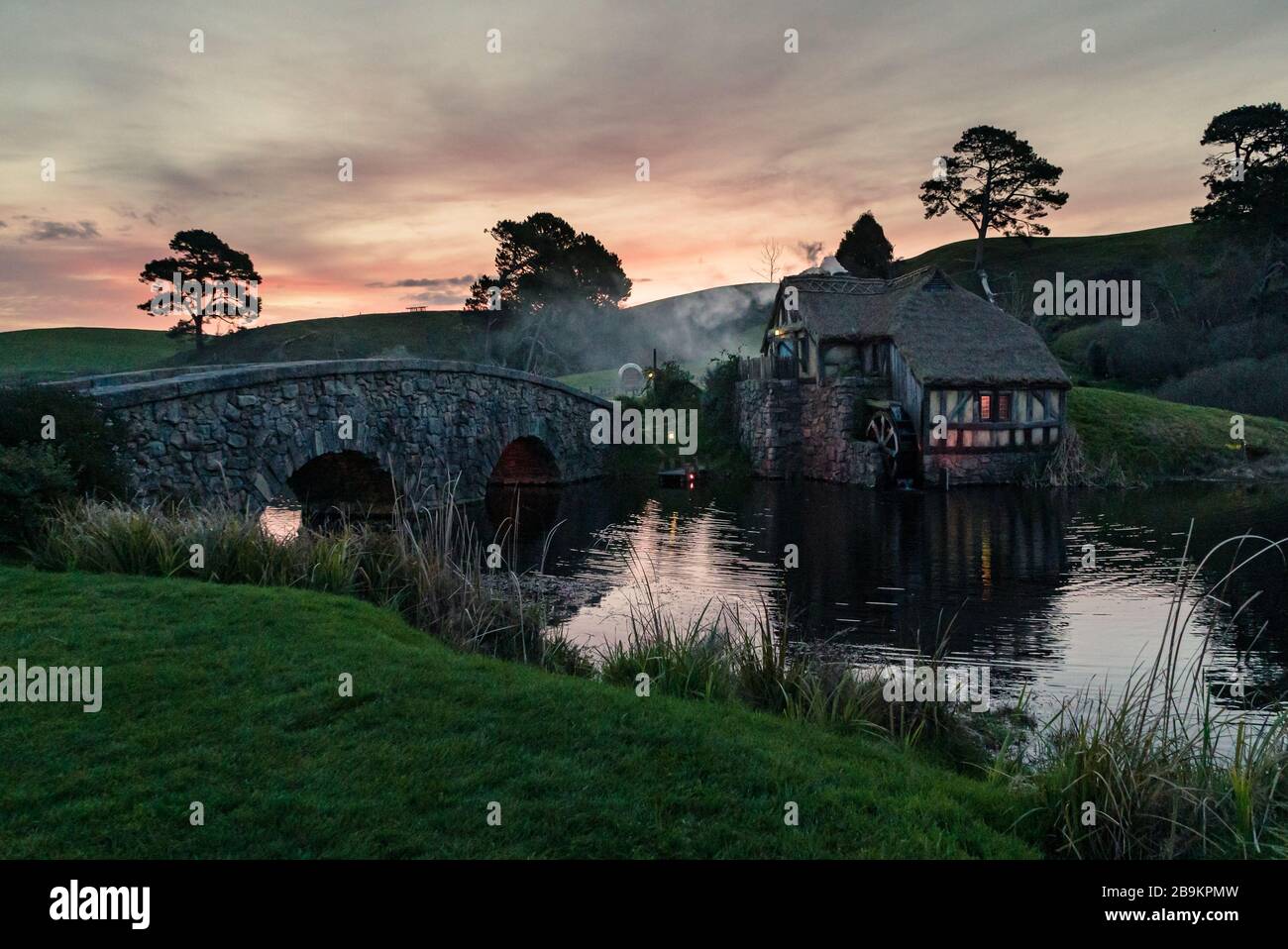 Sunset over the bridge and mill at the Hobbiton Movie Set, New Zealand Stock Photo