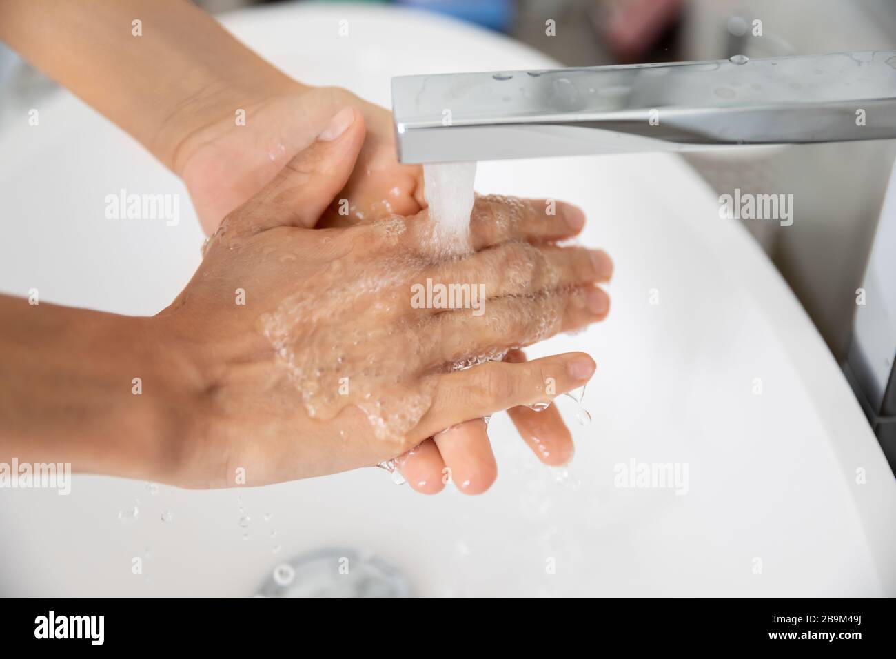 Closeup view caucasian woman cleans hands under running water Stock Photo