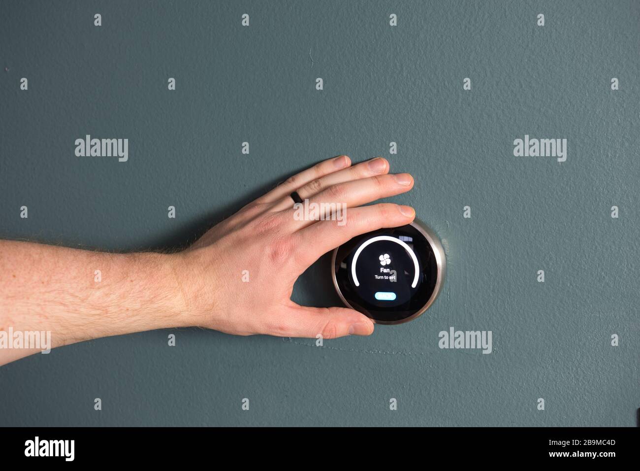 Green tech- Electric thermostat to save money and energy. Hand present to make adjustments Stock Photo