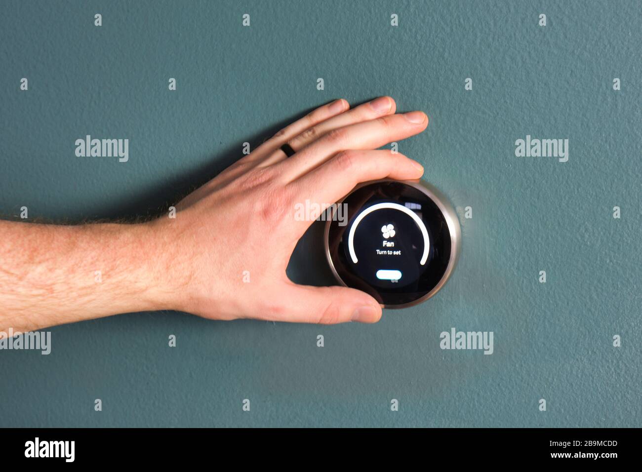 Green tech- Electric thermostat to save money and energy. Hand present to make adjustments. Stock Photo