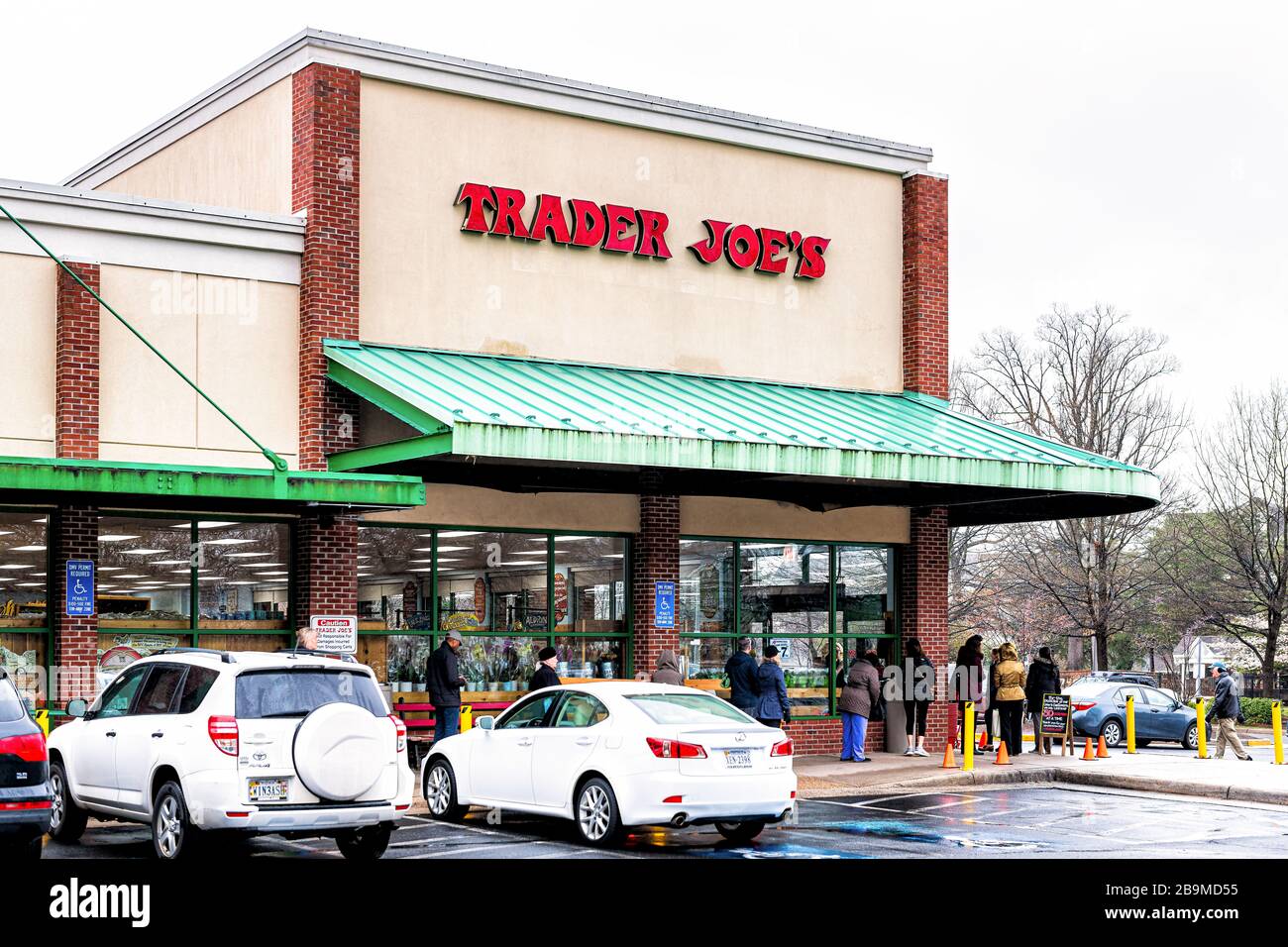 Reston, USA - March 23, 2020: Social distancing of people waiting in line queue by Trader Joe's grocery shop due to limit for customers in store durin Stock Photo