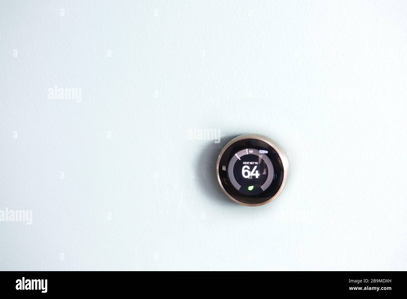 Smart home thermostat isolated on white wall. Temperature displayed to