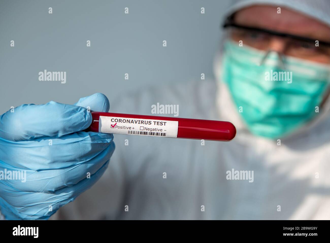 Laboratory technician man hand hold on positive blood sample tube for corona virus test , COVID-19. Scientist with protective suit and mask for protec Stock Photo