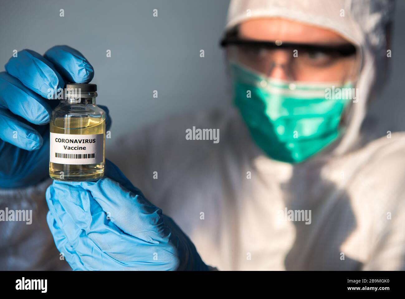Male scientific with protective suit holds a vaccine for coronavirus. Caucasian man with vaccination for COVID-19. 2019-nCoV found in Wuhan China. Epi Stock Photo