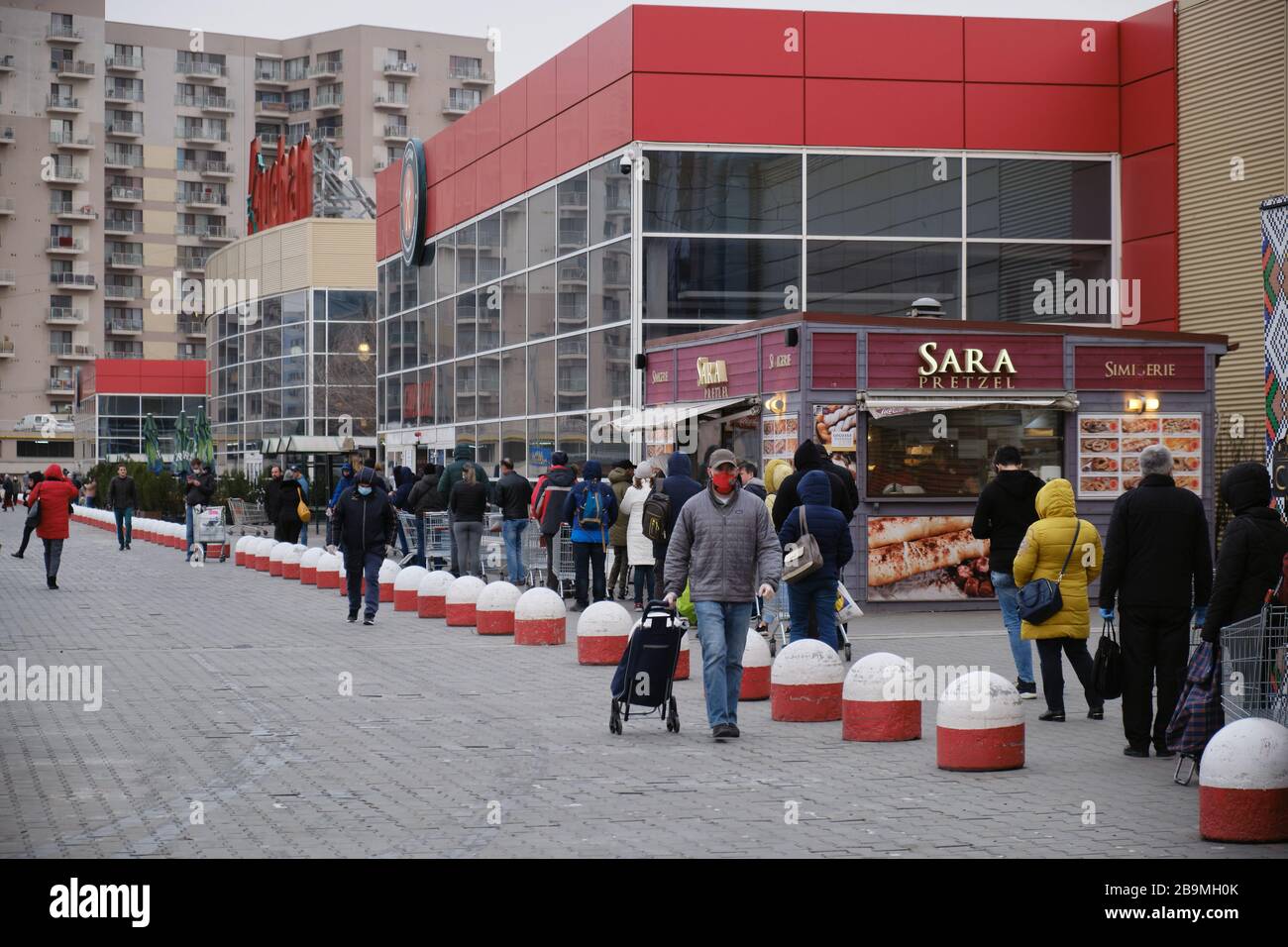 Bucharest, Romania - March 24, 2020: Shoppers stand in a queue outside a supermarket, after a Coronavirus lockdown is announced. Stock Photo