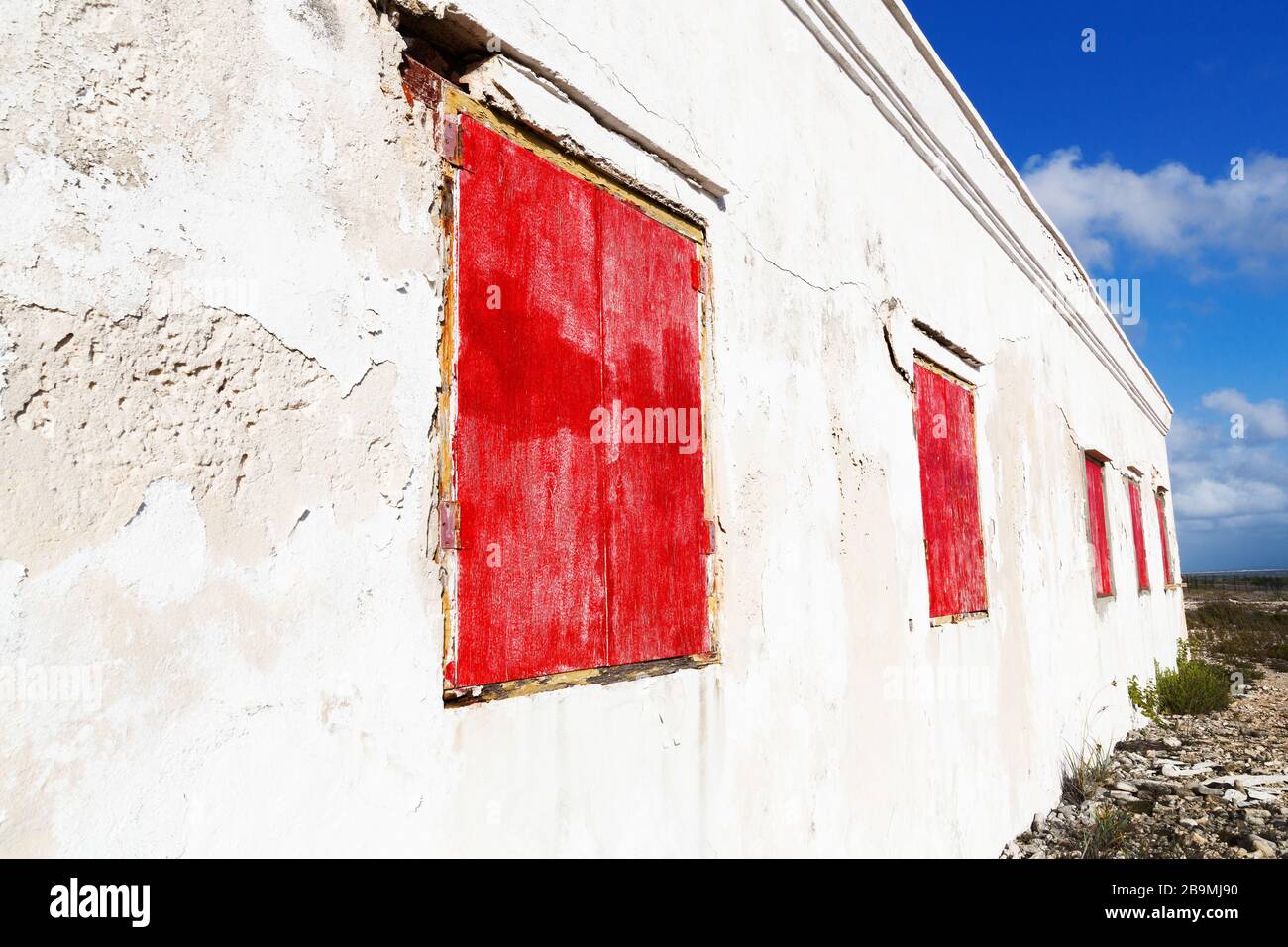 Older abandoned white house with red window shutters on the coast of Bonaire part of the ABC Islands, Netherlands Antillies, Caribbean Stock Photo