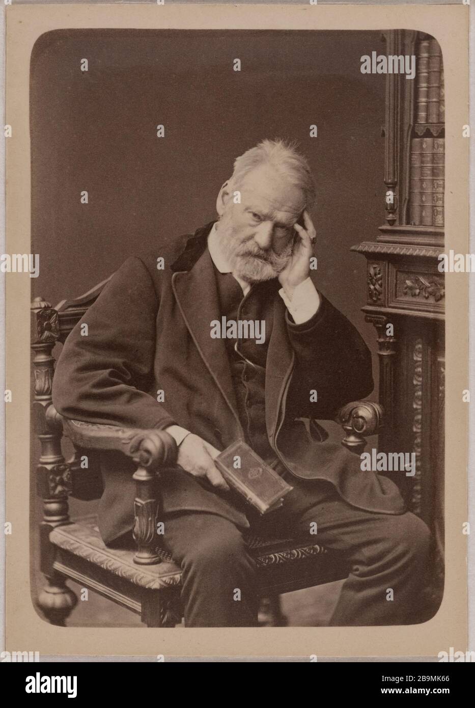 Victor Hugo seated next to face, left hand supporting his head, book in his right hand Lucien Waléry (1830-1890). Victor Hugo assis, regard de face, main gauche soutenant sa tête, livre dans la main droite. Epreuve sur papier albuminé ciré, 1879. Paris, Maison de Victor Hugo. Stock Photo