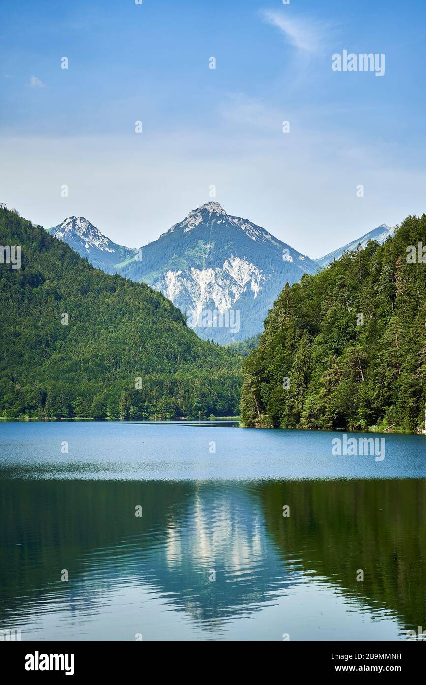 Alpsee lake near Hoehenschwangau and Neuschwanstein castle in Bavaria, Germany. A clear summer sky and Alps in the background. Stock Photo