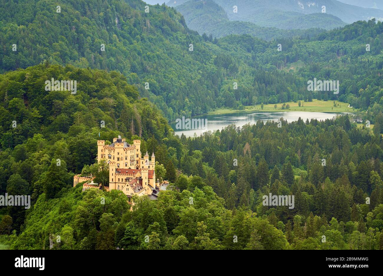 A view of a Hoehenschwangau castle surrounded by forest and a Swan lake in the background. Stock Photo