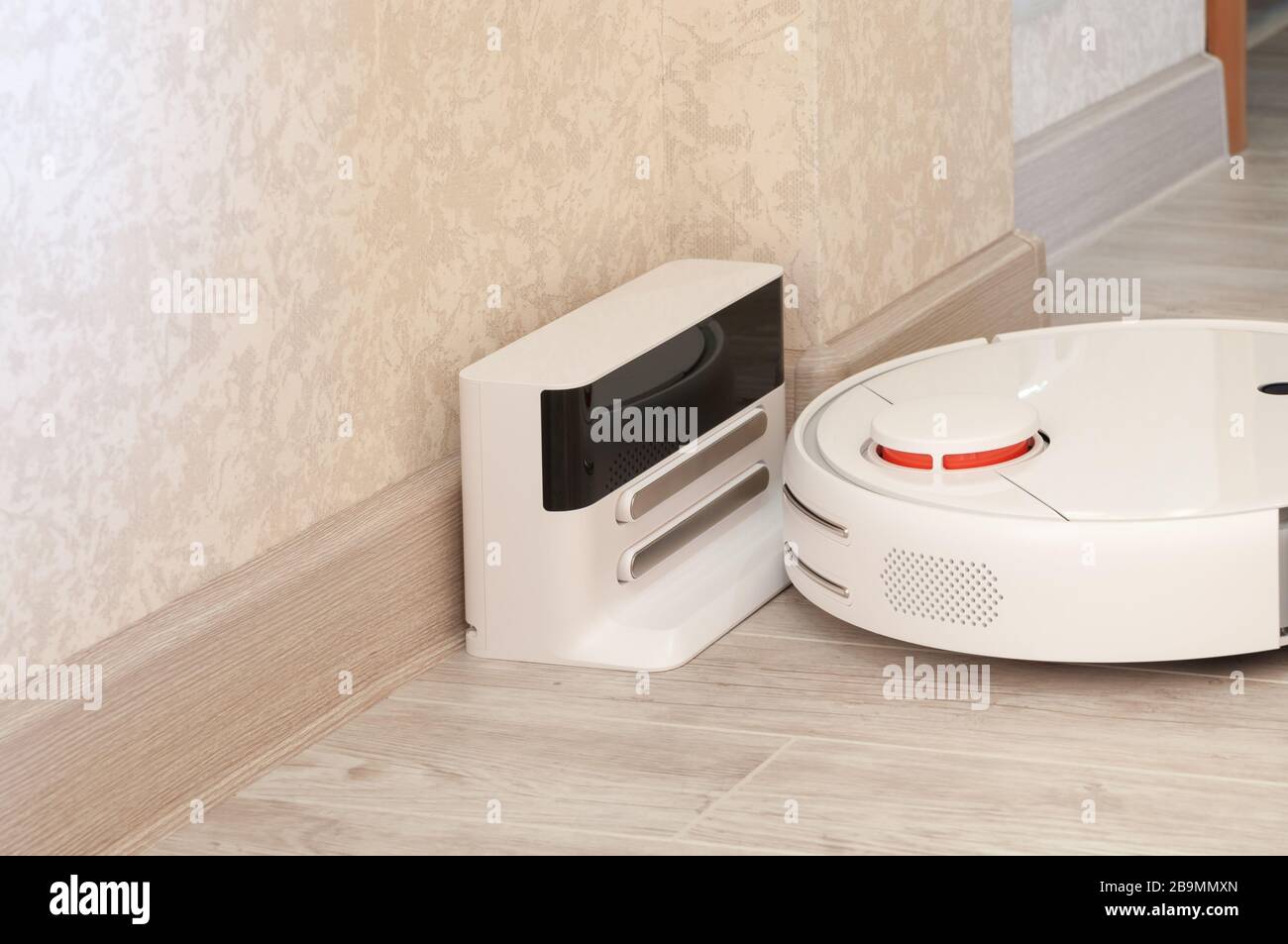 Robotic vacuum cleaner on laminate wood floor charging from base station. smart cleaning