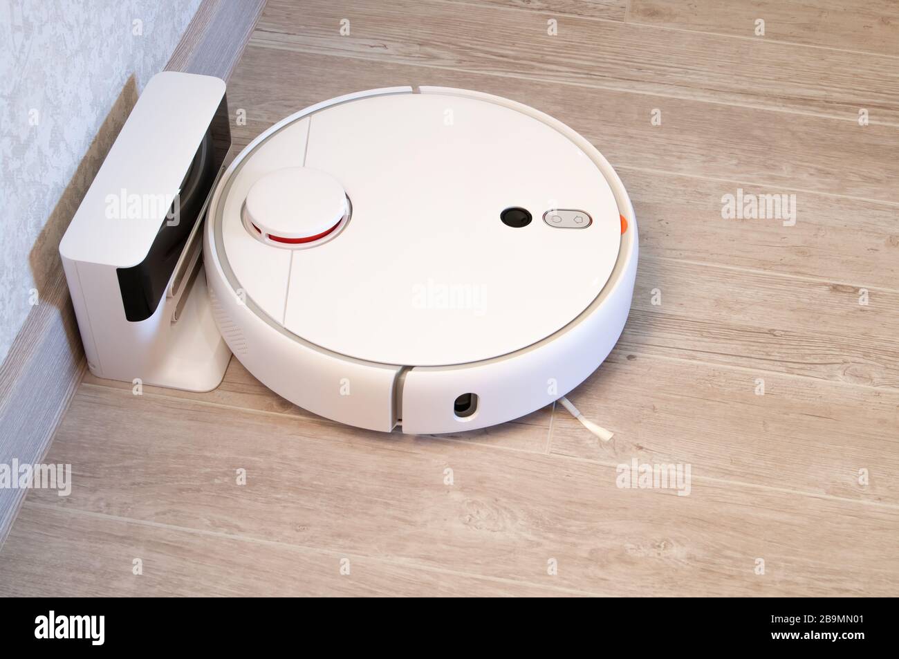 Robotic vacuum cleaner on laminate wood floor charging from base