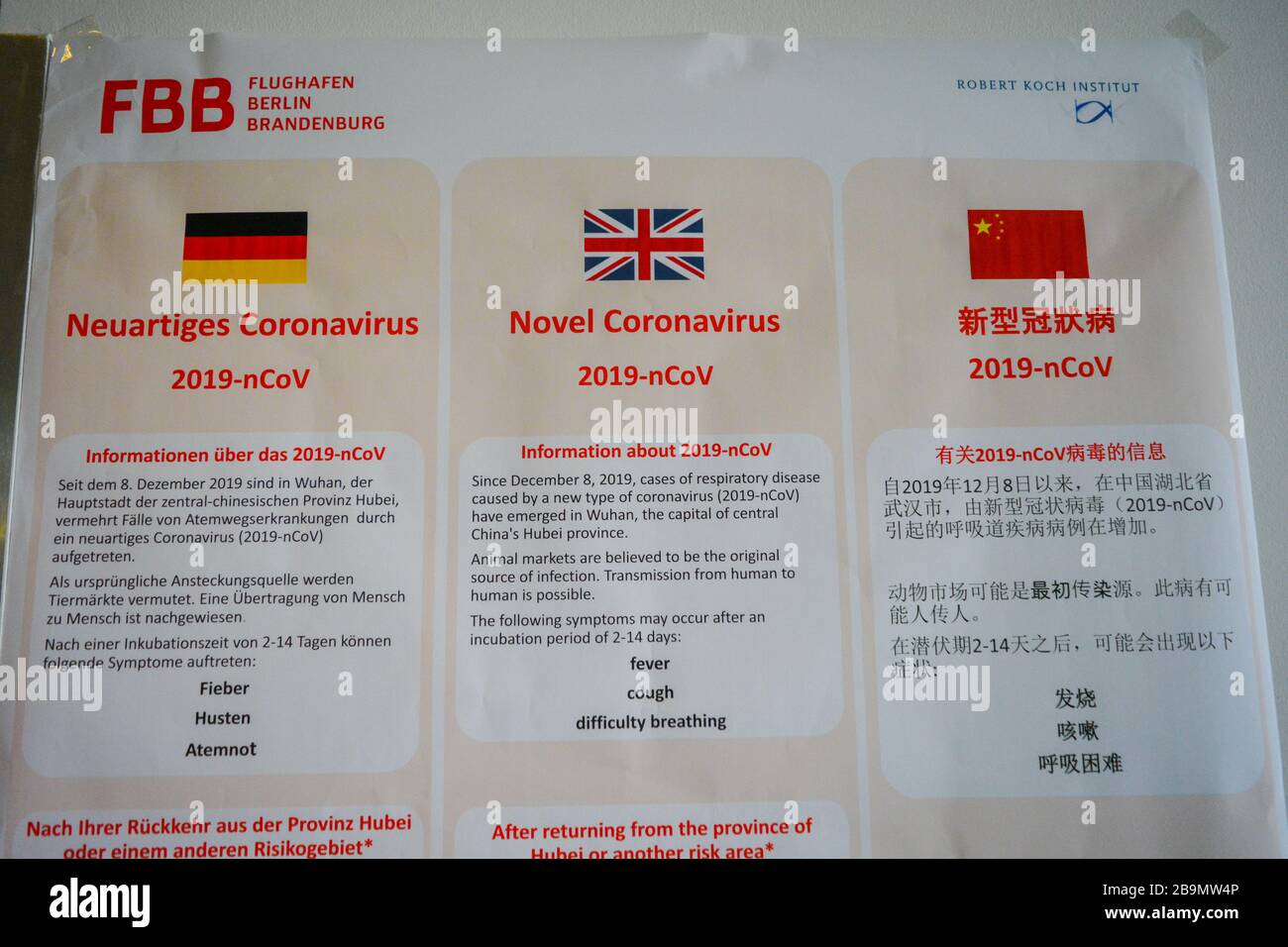 Berlin Schonefeld Airport SXF, Germany: Warning official billboard informs on Coronavirus COVID-19 to  airport travellers. In German, English,Chinese Stock Photo