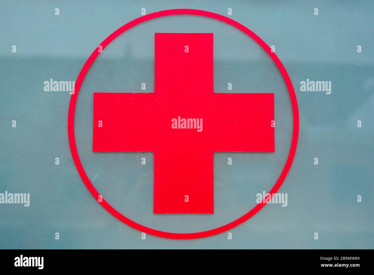 Closeup of a red cross over a beautiful gray glass on the back of an ambulance. Symbol of medicine and healthcare. Window of emergency vehicle. Entran Stock Photo