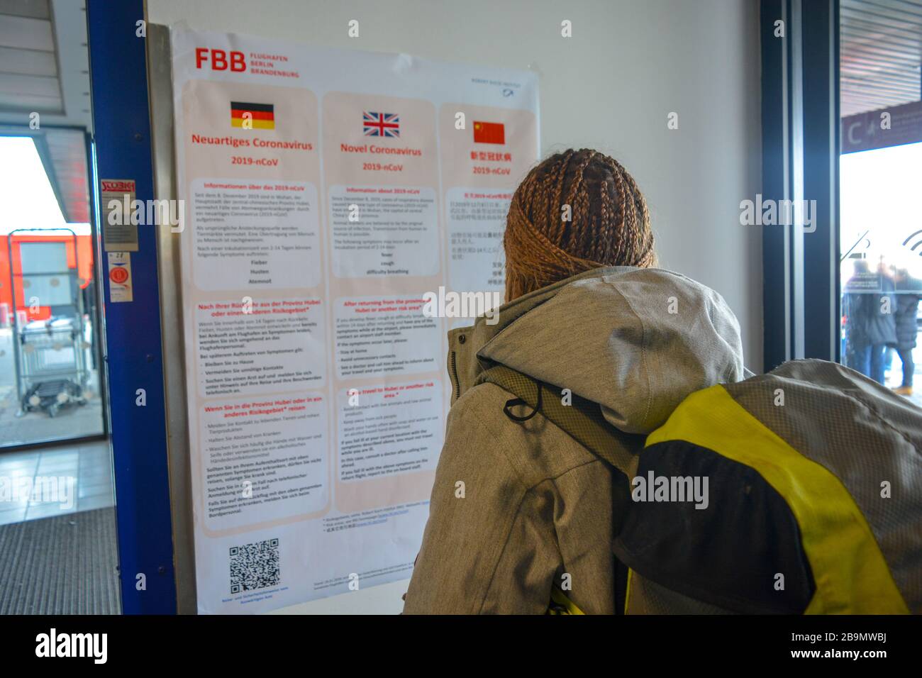 Berlin Schonefeld Airport SXF, Germany - 02/01/20: A warning public notice about Coronavirus 2019-nCoV in the airport terminal read by a traveller. Stock Photo