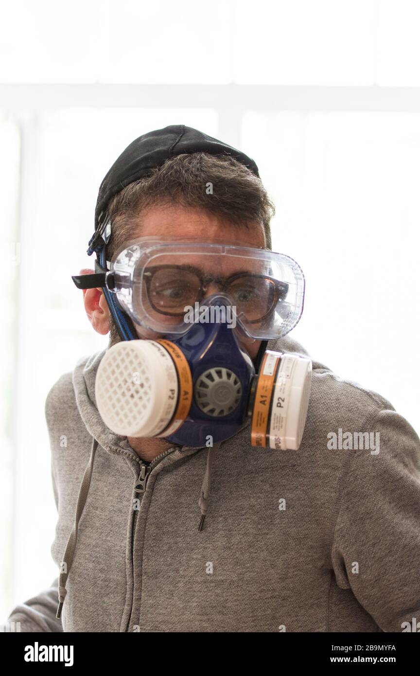 Jewish man wearing a yarmulke in full gas mask and goggles as silly protection against covid-19 corona virus Stock Photo