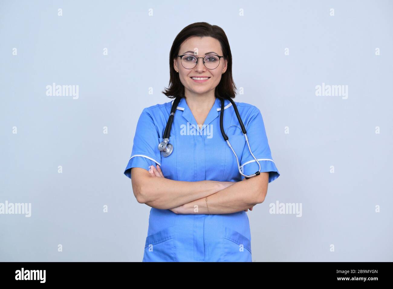 Portrait of nurse woman in blue uniform with arms crossed, confident ...