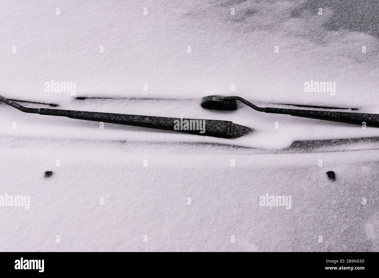 Snow covered windshield with wiper blades. Concept of driving in winter time with snow on road. Winter season. Stock Photo