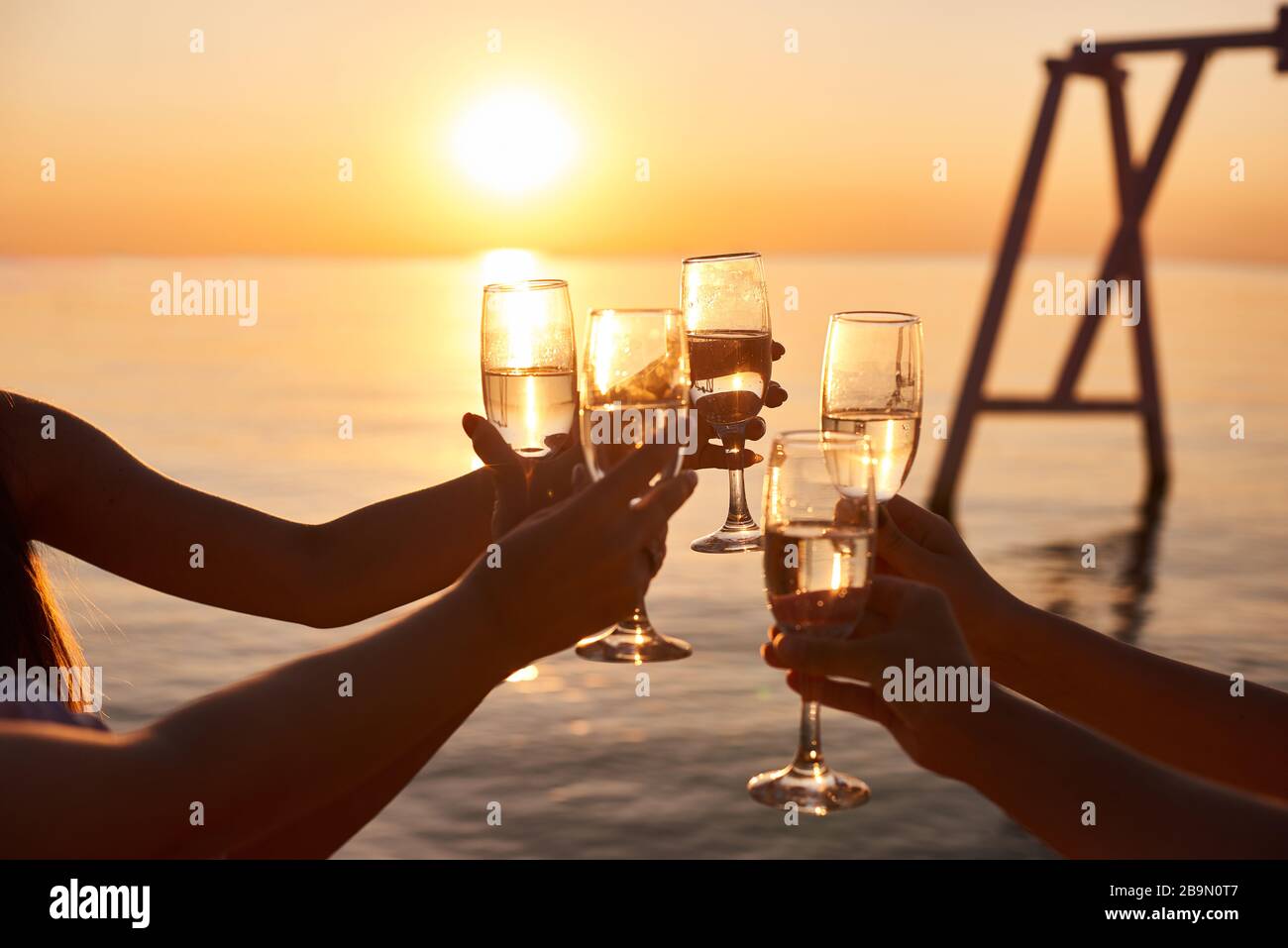 Happy young women drinking champagne at bachelorette party on the beach. Bride and bridesmaid having fun at hen party Stock Photo