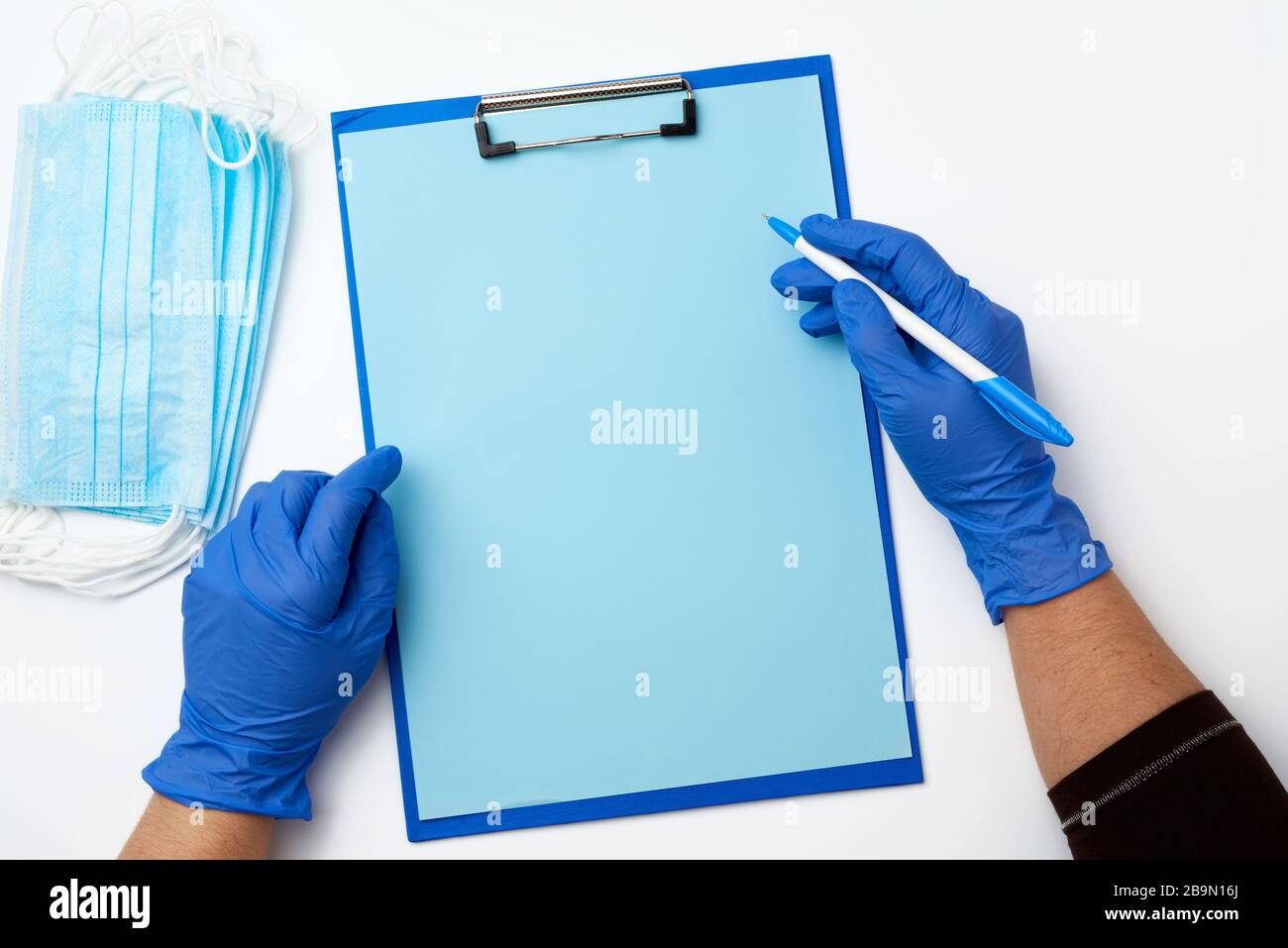 female hand in blue sterile gloves , on the table is a paper holder ...