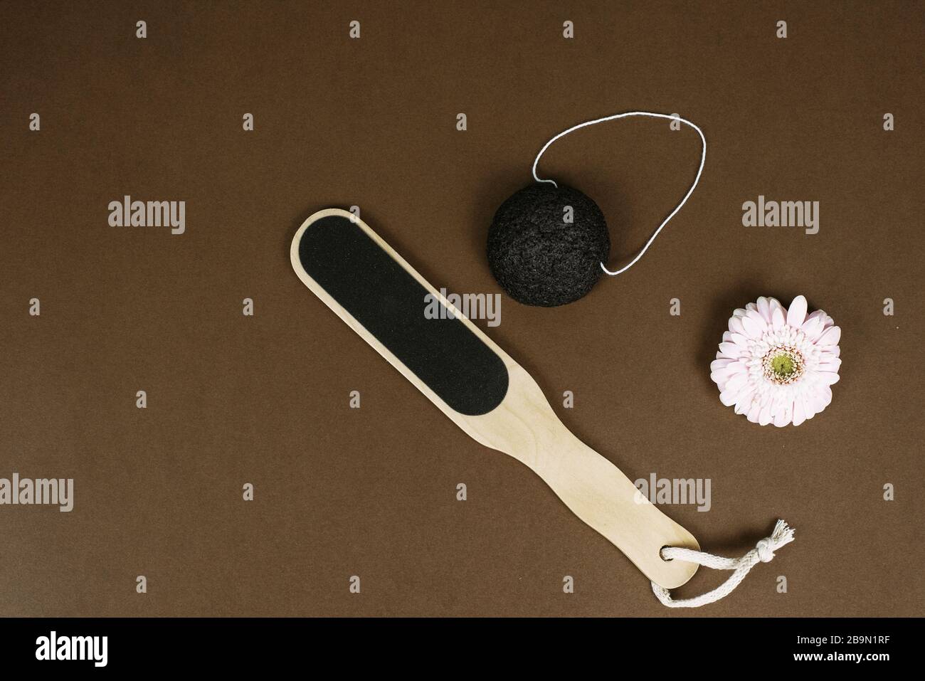 Different natural pumice for exfoliating the skin lies on a brown background next to the flower with copy space. The concept of moisturizing the skin of the feet with natural ingredients. Stock Photo