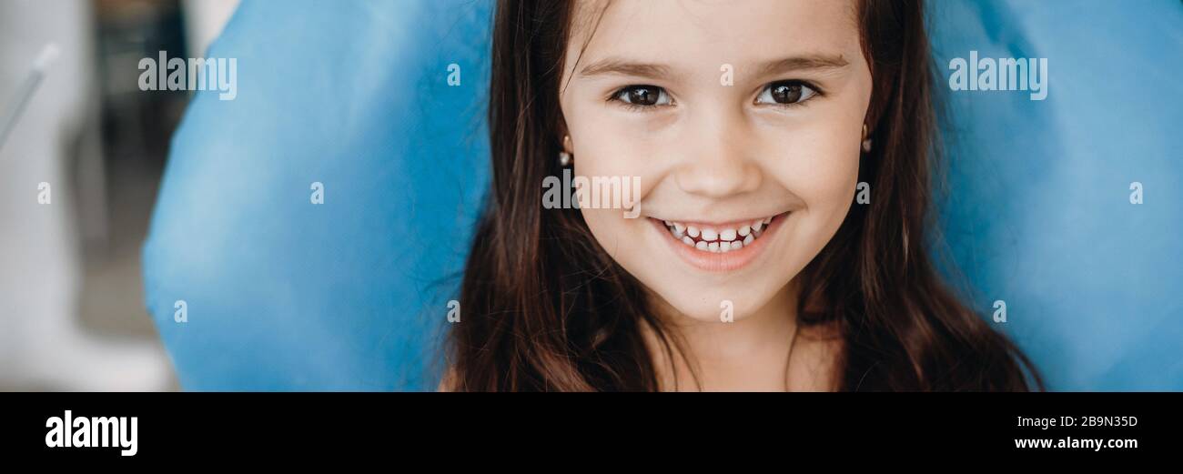 Happy caucasian small girl looking and smiling at camera after a dental ...