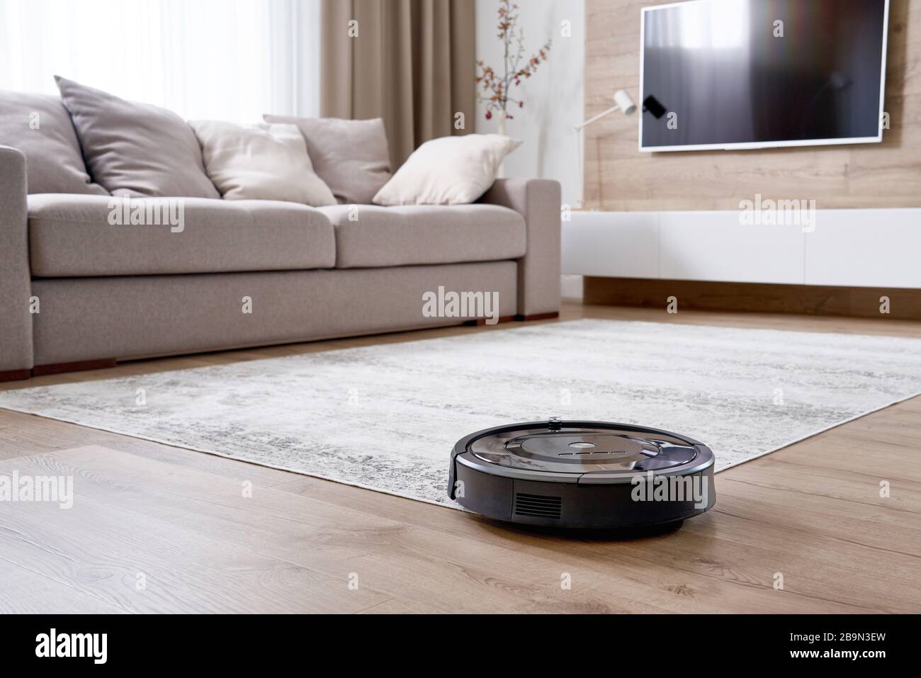 Robotic vacuum cleaner on the floor in cozy modern living room Stock ...