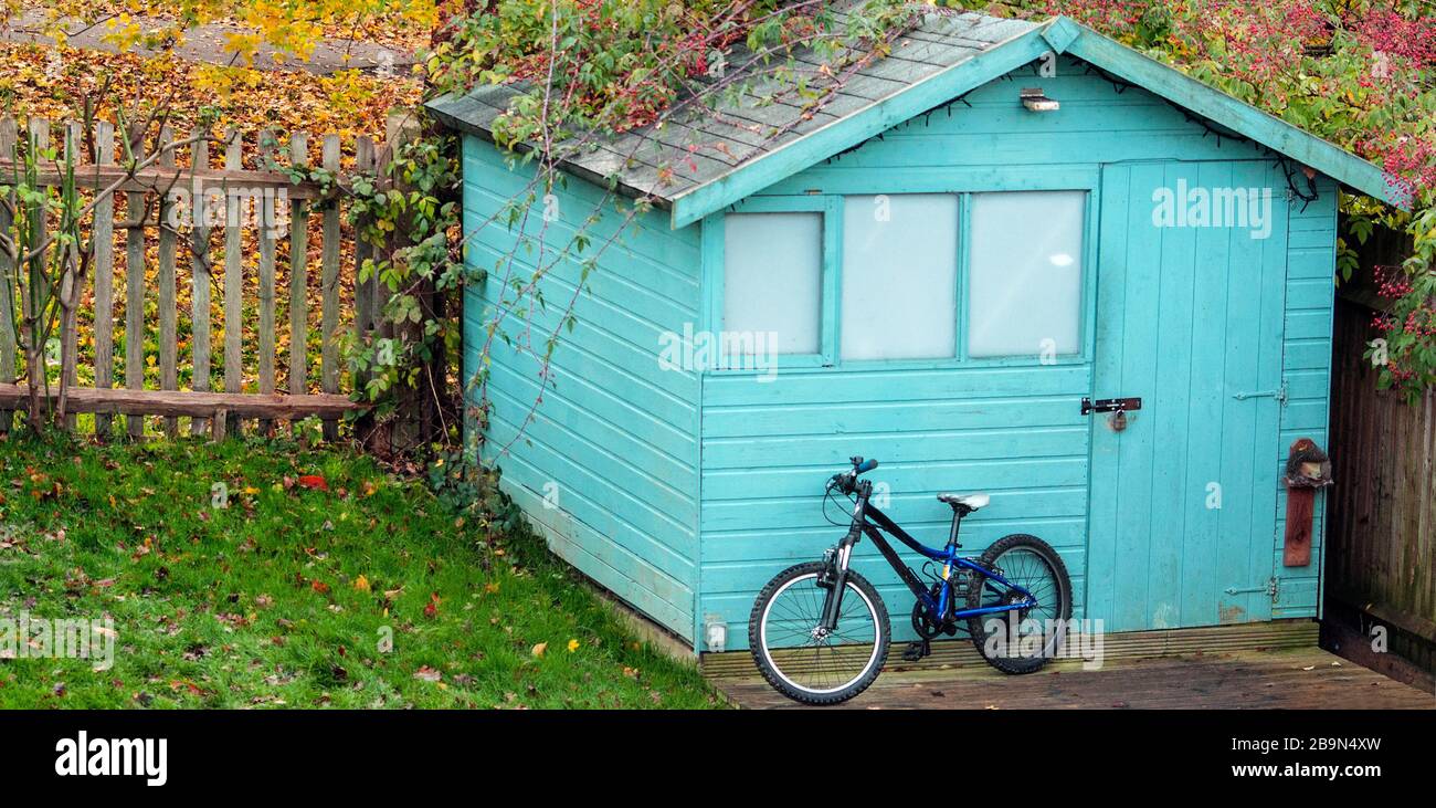 Bike parked in front of a shed in a garden. Means of transportation Stock Photo