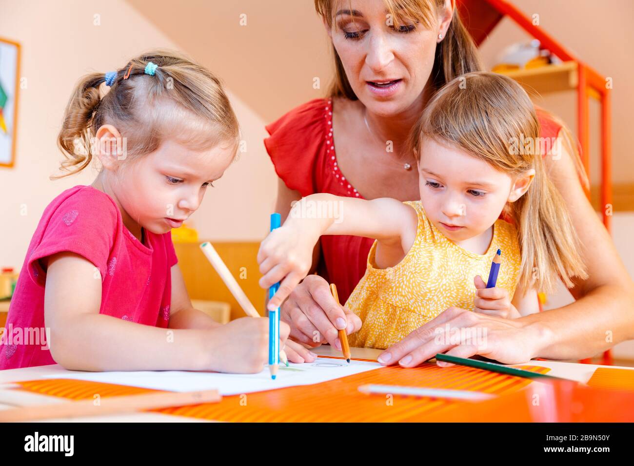 Children and play school teacher drawing together Stock Photo