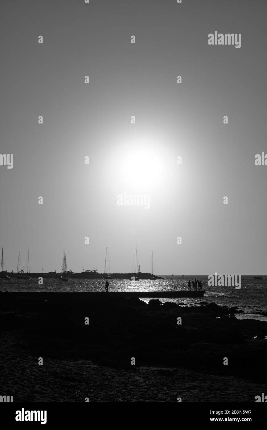 a view of the sunset in the atlantic sea behind the boats and sails from the rocks of the port of Punta del Este, Maldonado, Uruguay Stock Photo