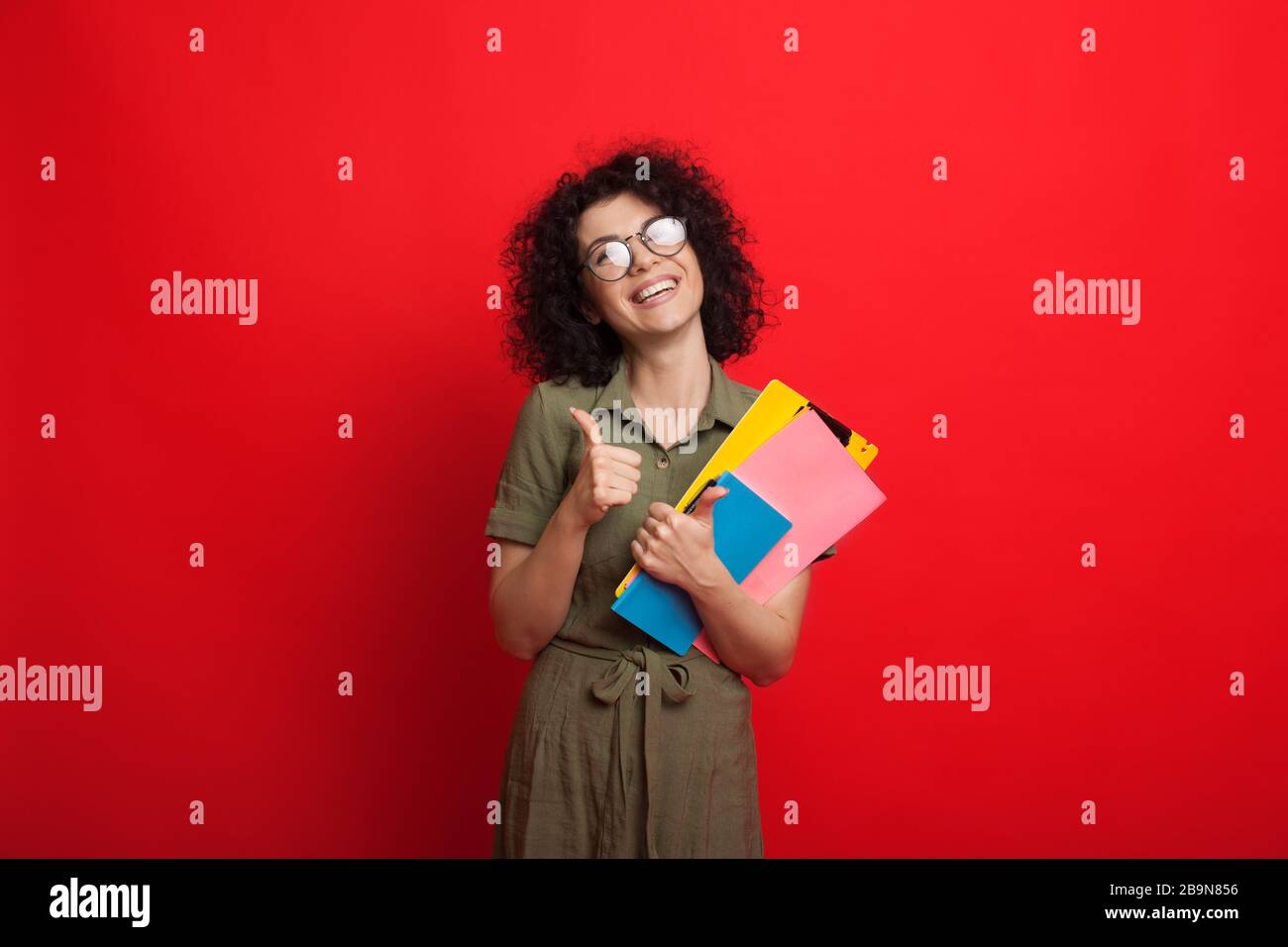Curly haired caucasian student is holding some books and gesturing the ...