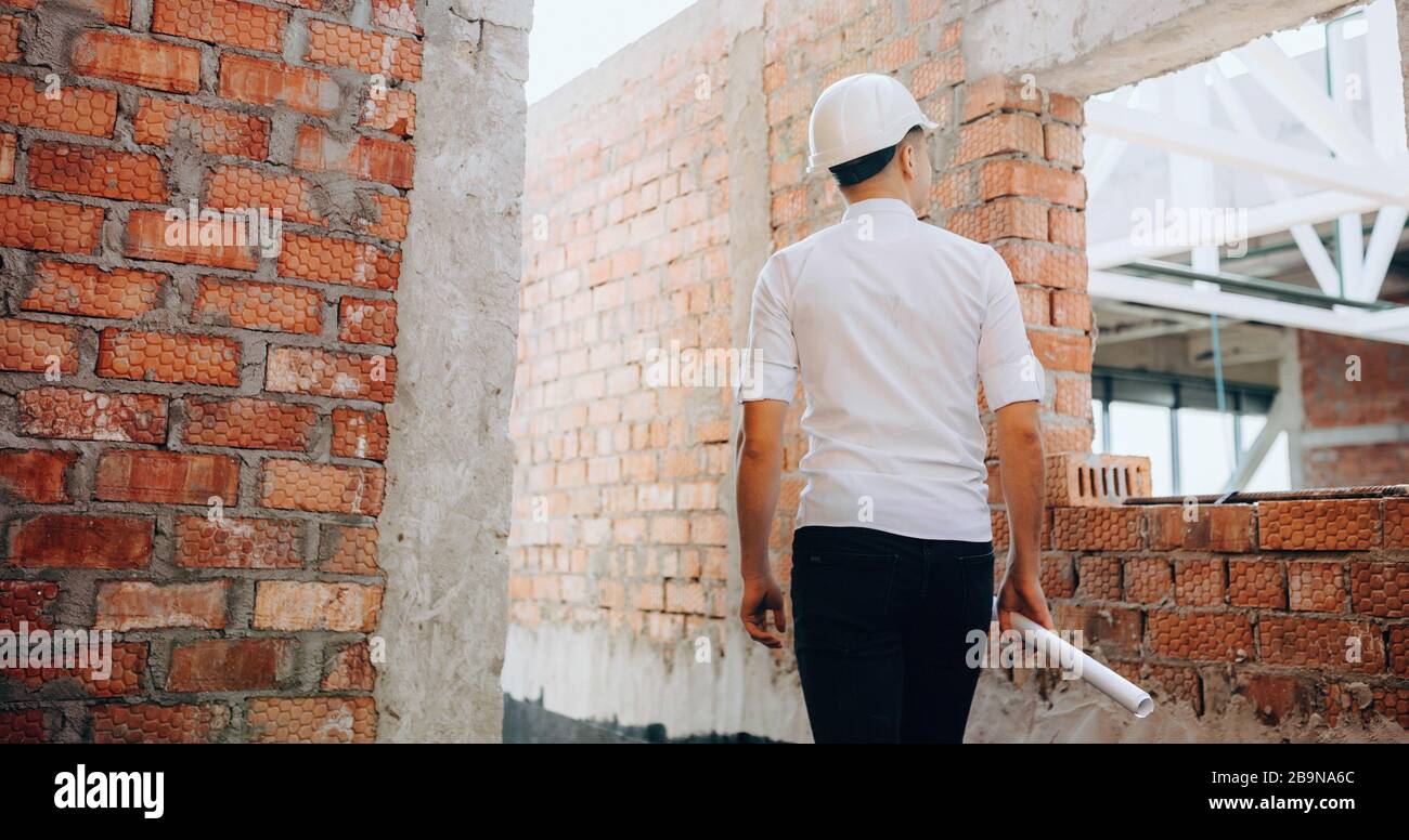 Young caucasian inspector verifying the job while holding a map and looking around Stock Photo