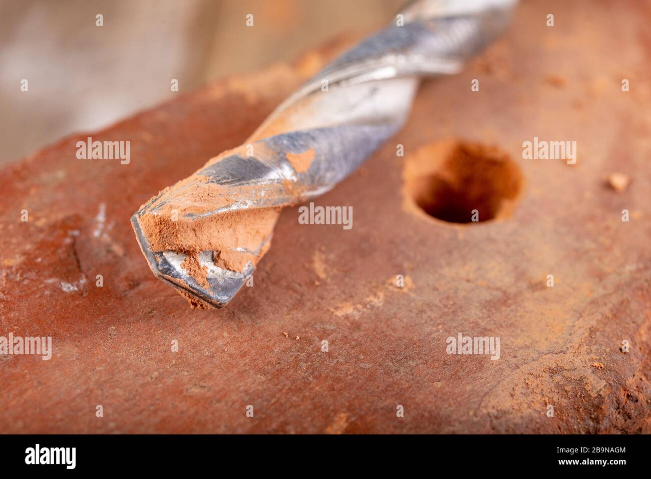 Drilling a hole in a clay brick. Carbide drill and red brick. Light