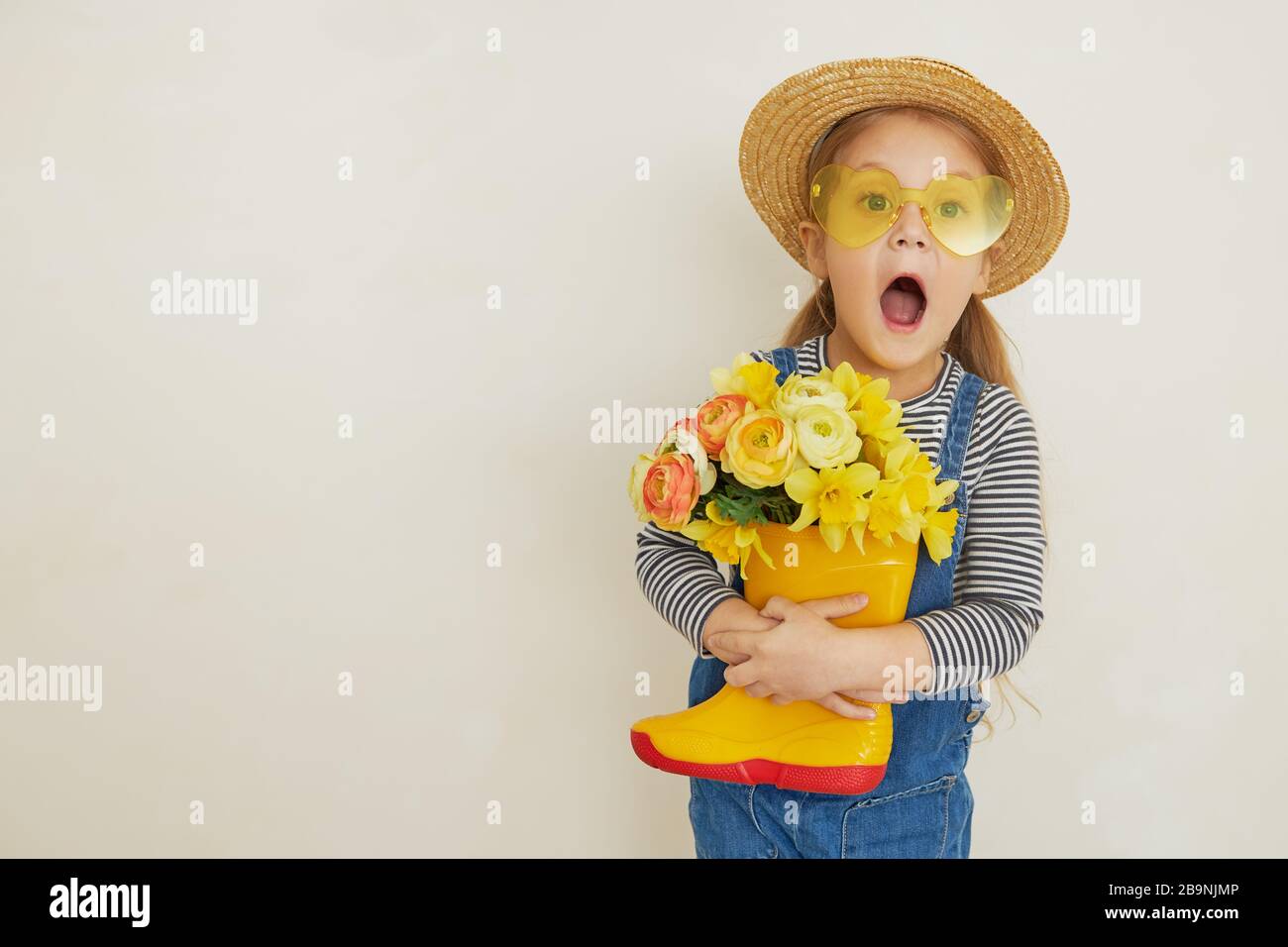 Little surprised child girl in straw hat with a bouquet of yellow ...