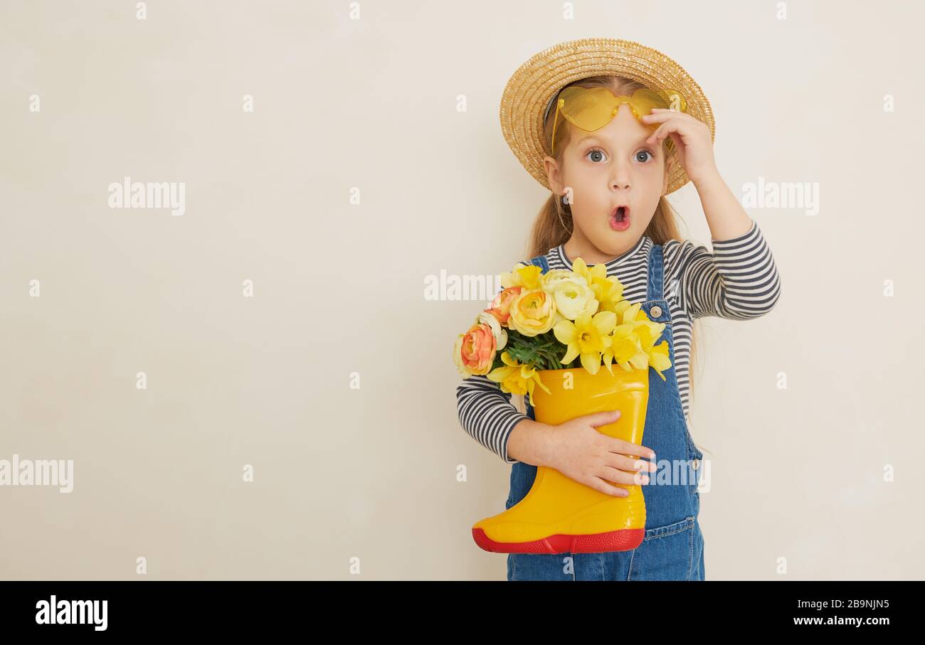 Little surprised child girl in straw hat with a bouquet of yellow ...
