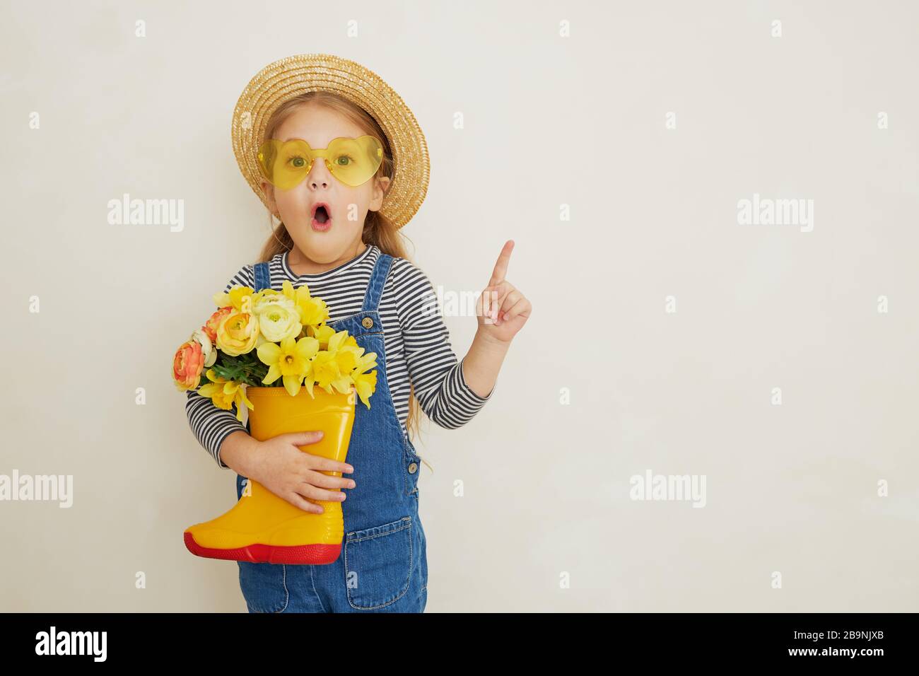 Little surprised child girl in straw hat with a bouquet of yellow ...
