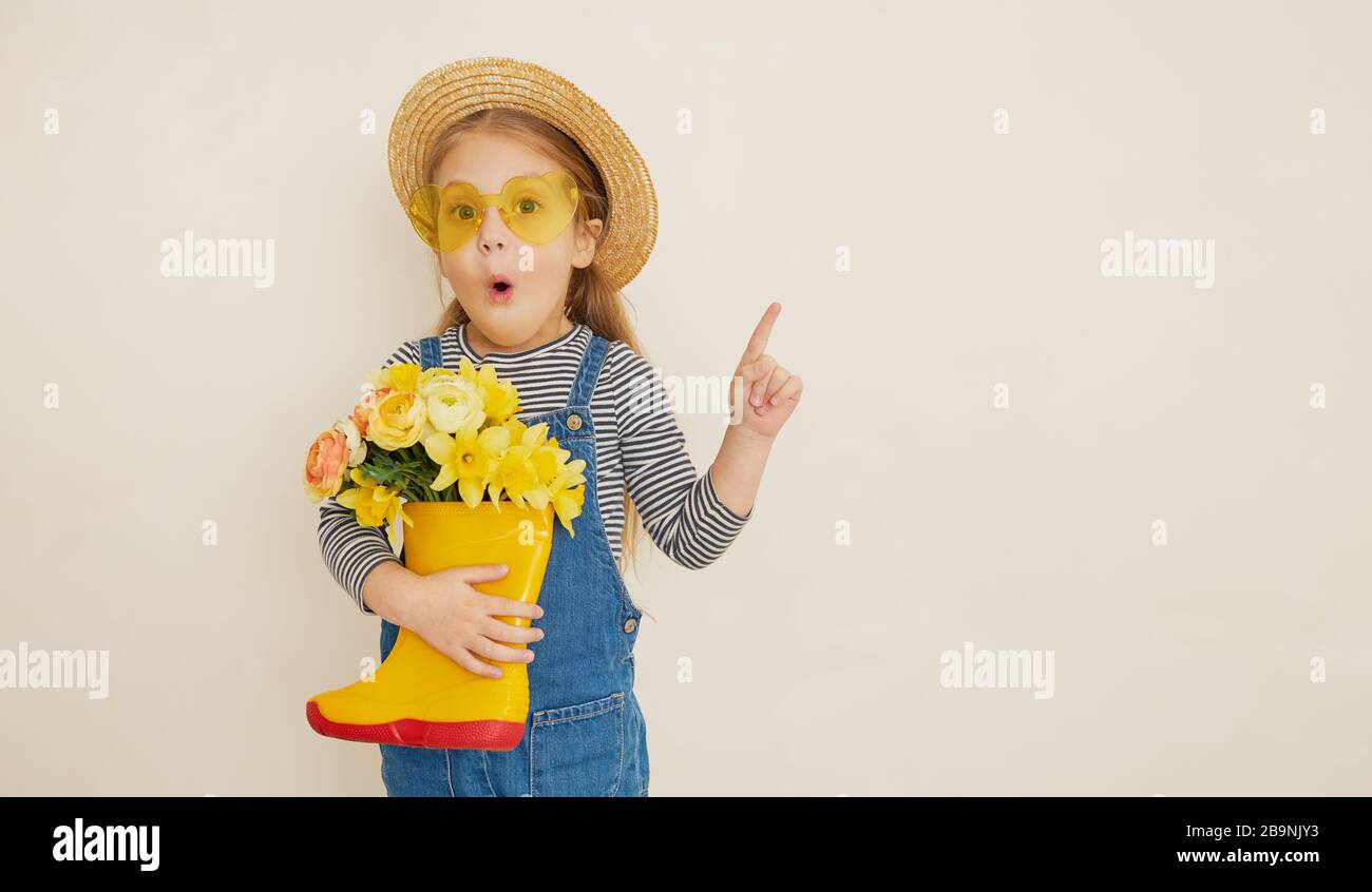Little surprised child girl in straw hat with a bouquet of yellow ...