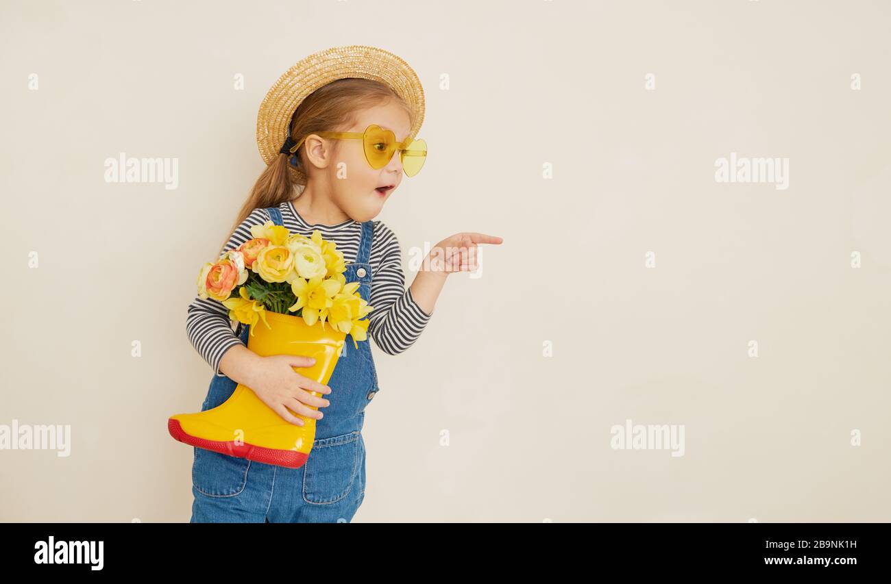 Little surprised child girl in straw hat with a bouquet of yellow ...