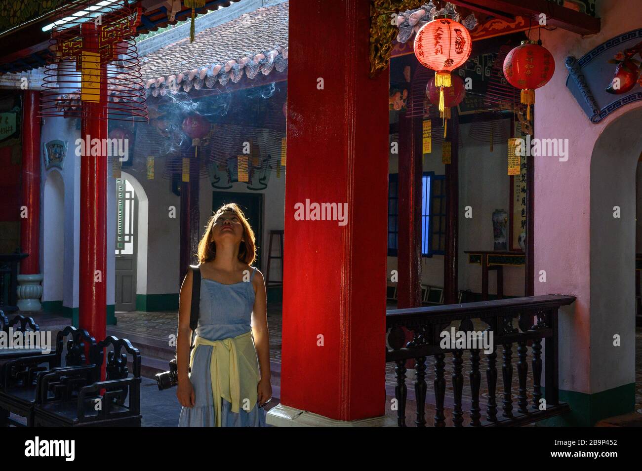 A Vietnamese female traveler looking at the interior of a temple, Hoi An, Vietnam Stock Photo