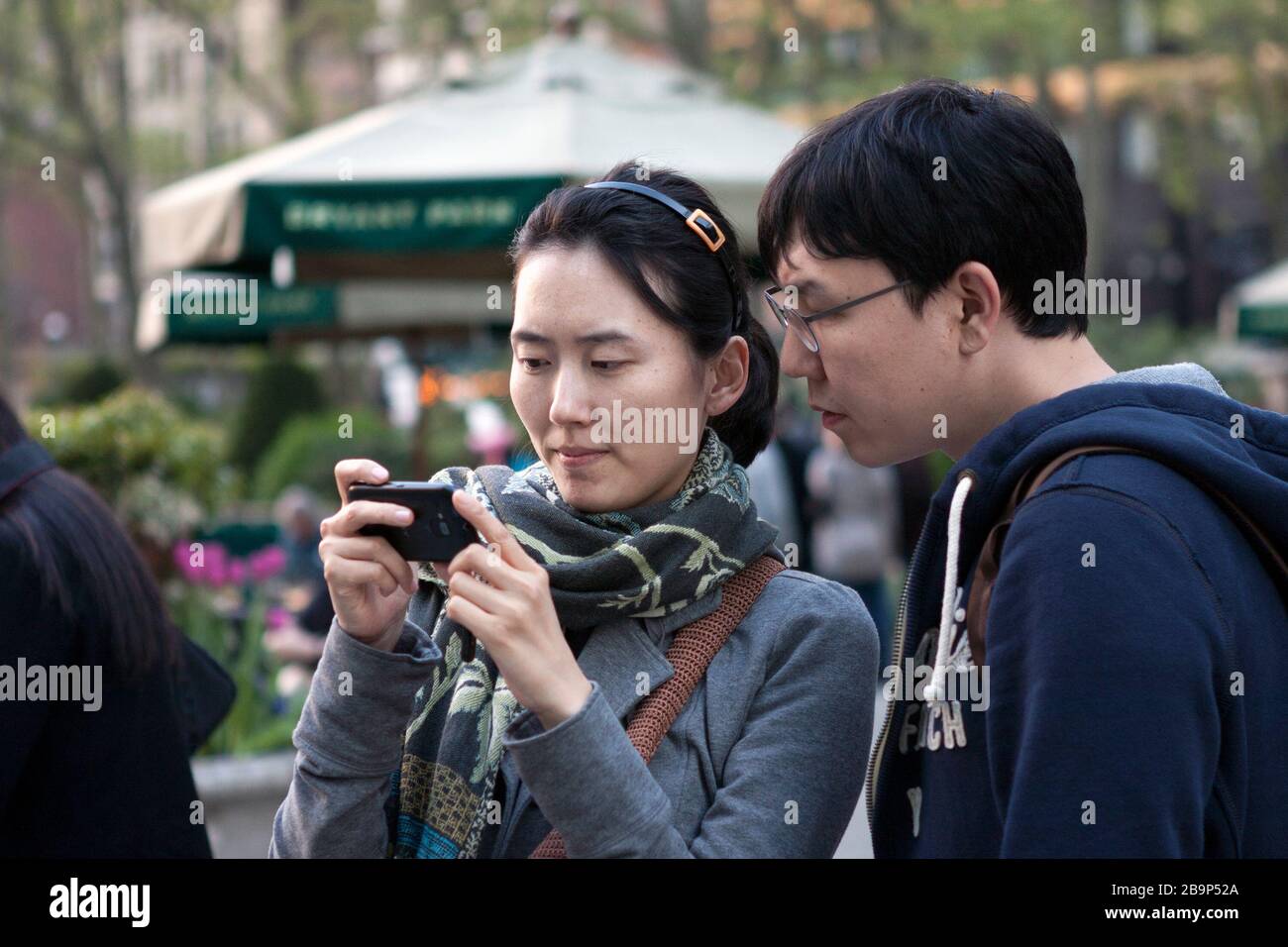 A young couple looks at their phone in Bryant Park in New York City. Stock Photo