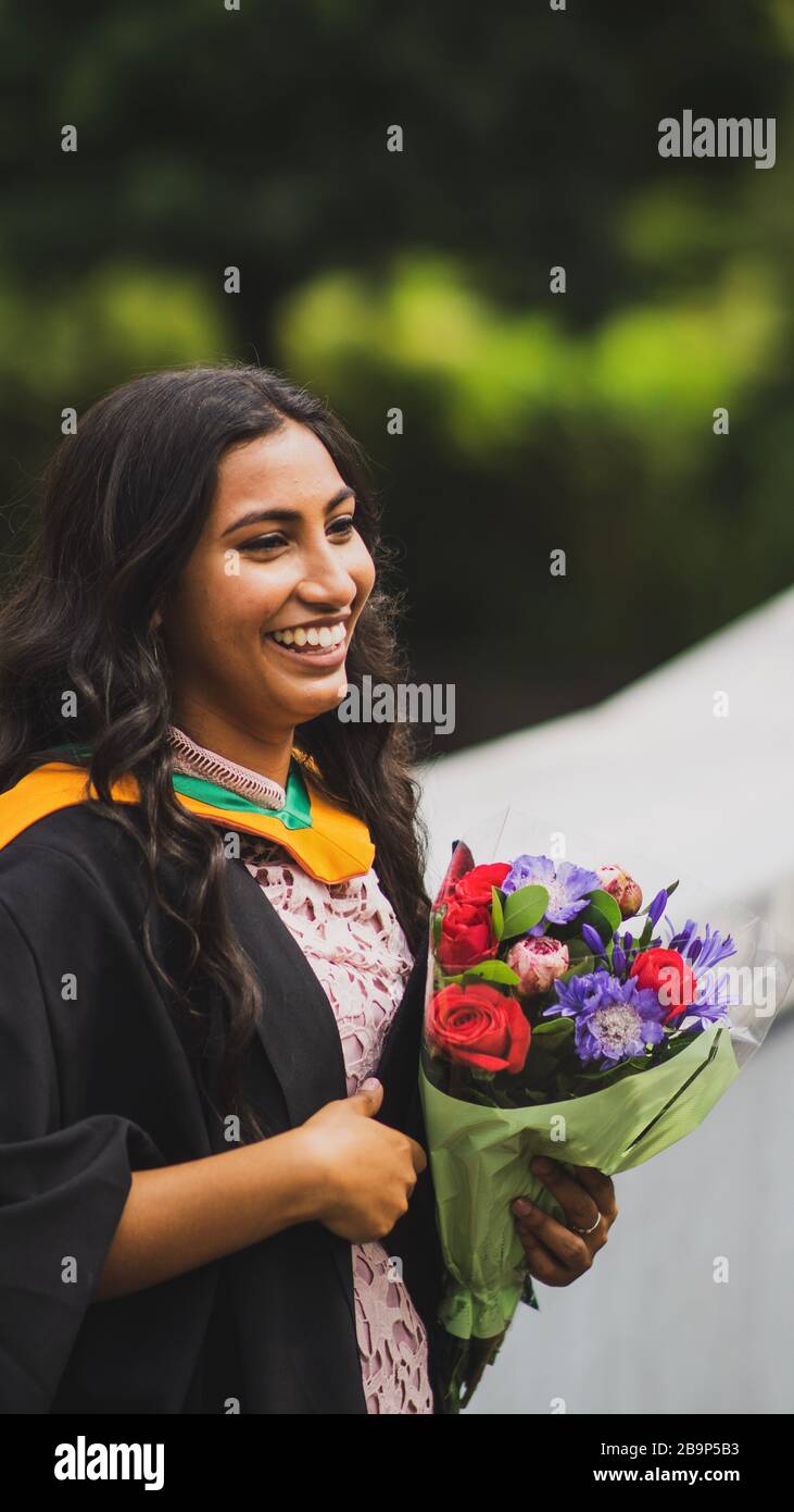 Graduation photographs of an Indian woman outdoors, with flowers. Stock Photo