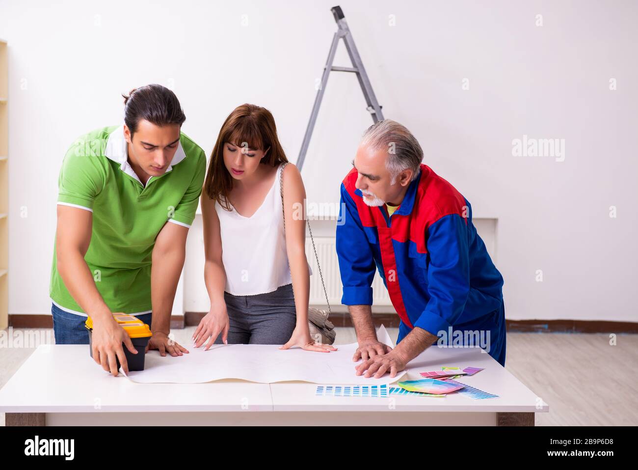 Young couple and old contractor in the home renovation concept Stock Photo