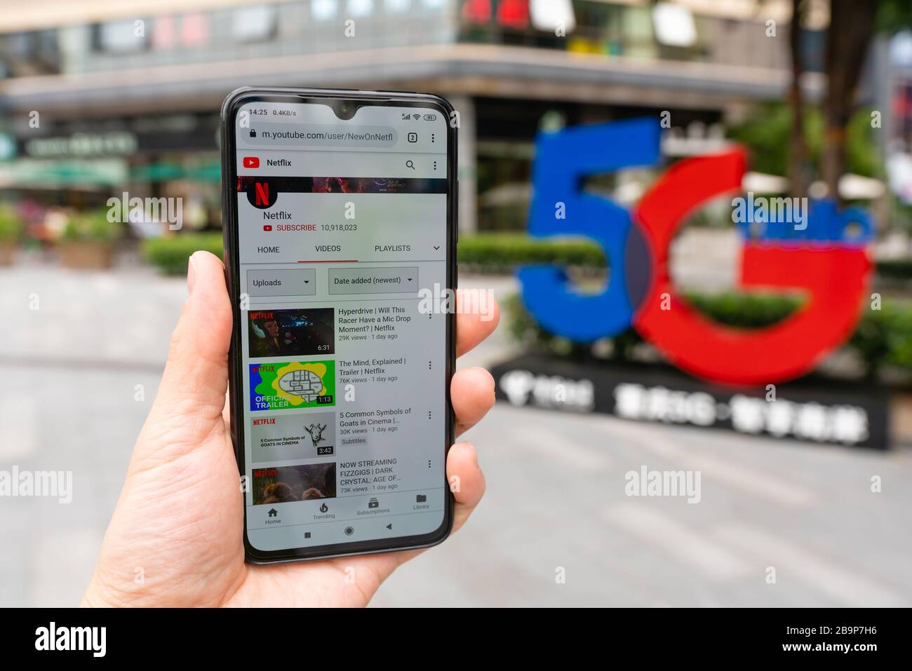 Using smartphone in front of 5G sign Stock Photo