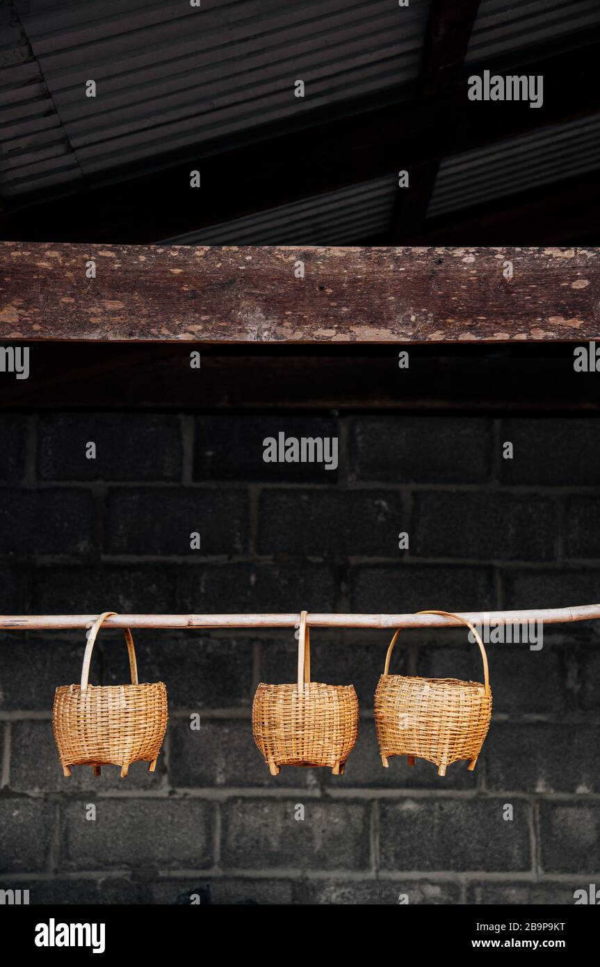 Asian style Wicker bamboo rattan basket with wooden handle hanging on bamboo stick in farmer house Stock Photo