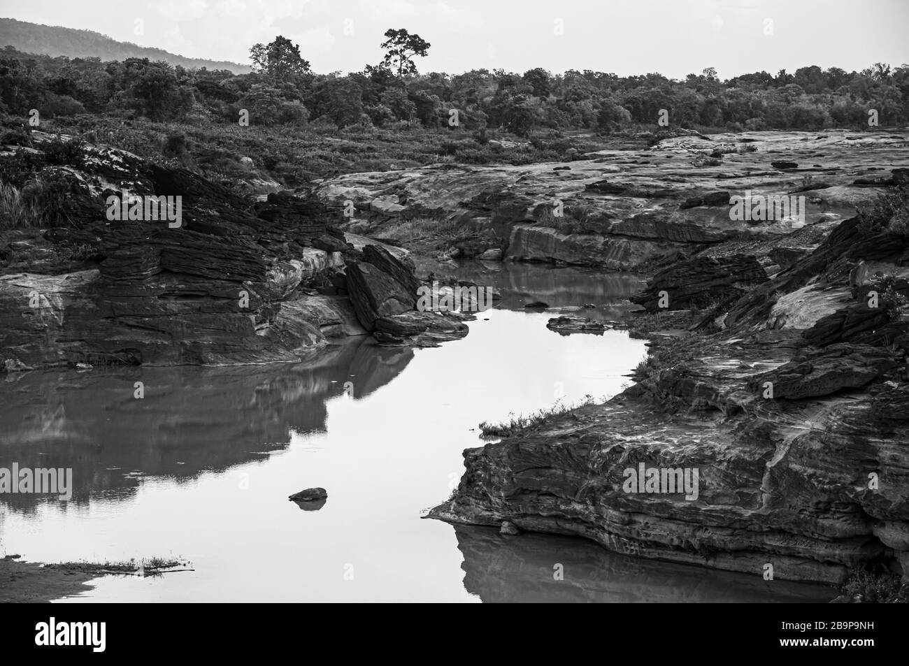 Large Sand stone canyon cliff shoreline of Mekong river under evening lighton cloudy day at Ban Pha Chan, Ubon Ratchathani, Thailand. Black and white Stock Photo