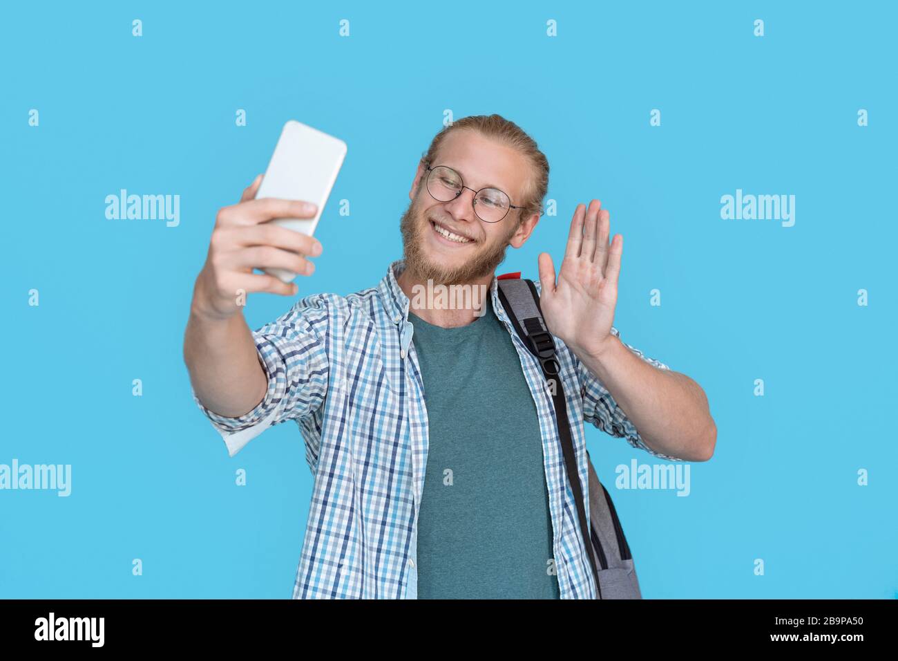 Handsome young man making selfie waving hand. Stock Photo