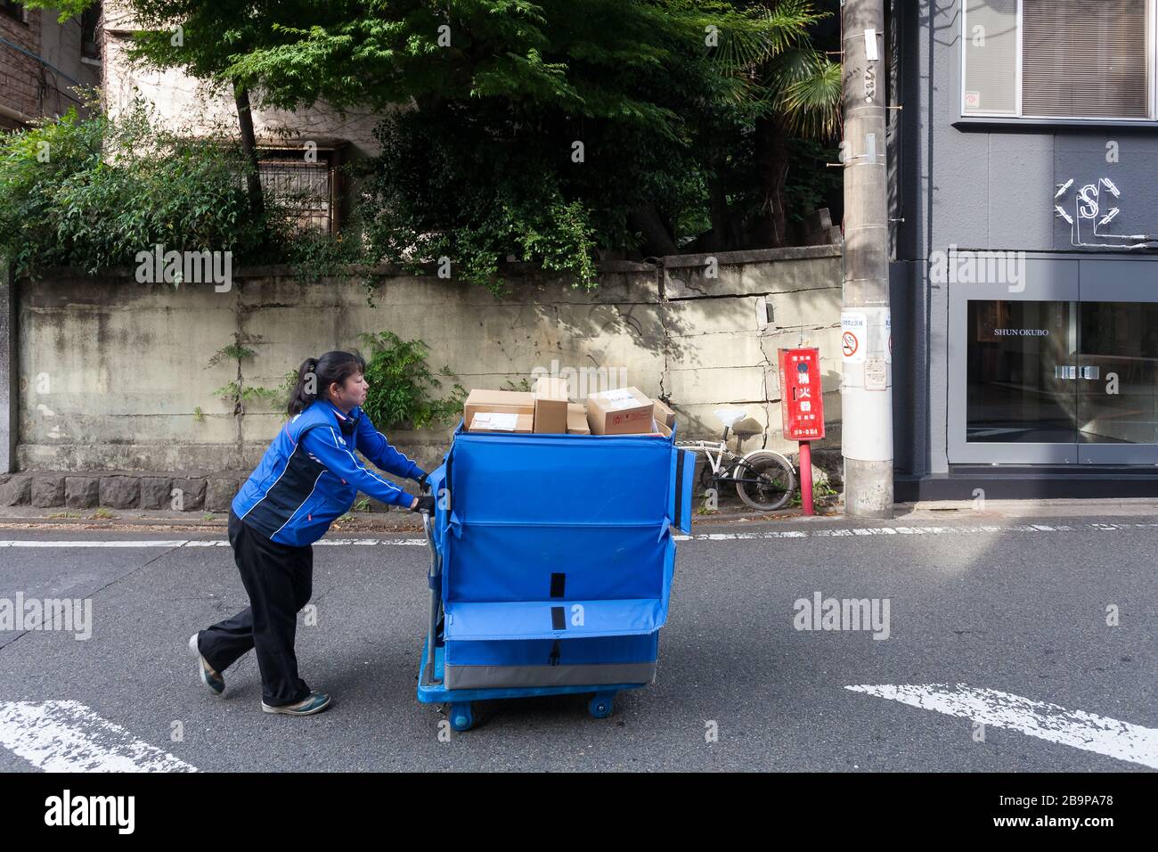 A woman working for Sagawa Express delivery company pushes a cart filled with parcels in a