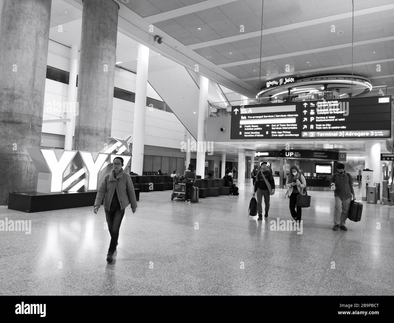 Air travellers, some wearing facial masks, lingering in Terminal One in Toronto Pearson International Airport during pandemic of Covid-19, a.k.a novel coronavirus on March 24, 2019. Stock Photo
