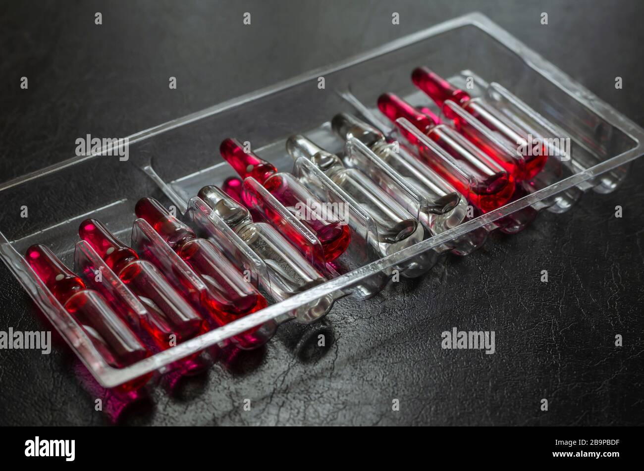 Multicolored ampoules with medicines on a dark background. Glass