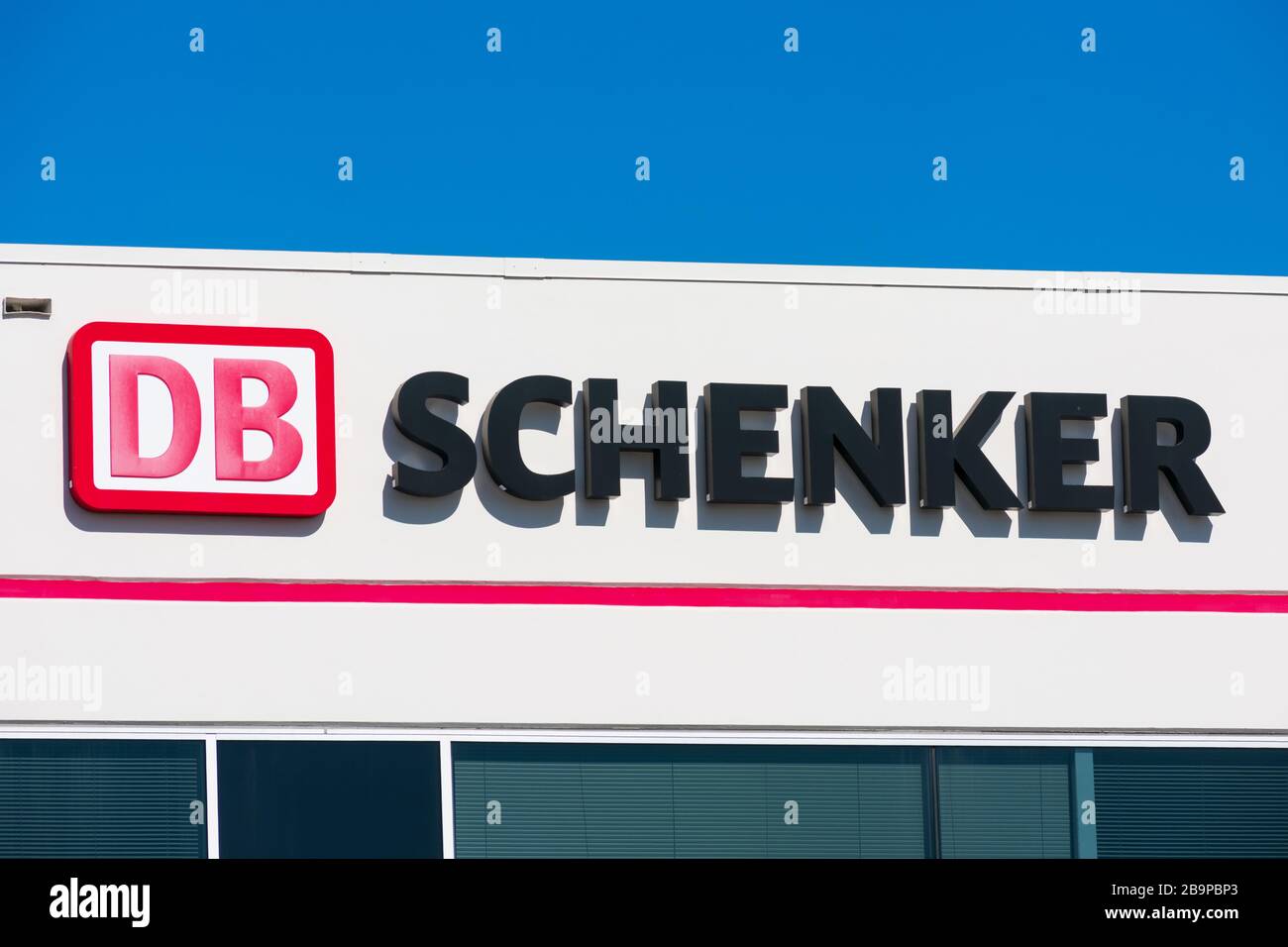 DB Schenker sign on transportation service office. DB Schenker is a division of the German rail operator Deutsche Bahn AG that focuses on logistics - Stock Photo