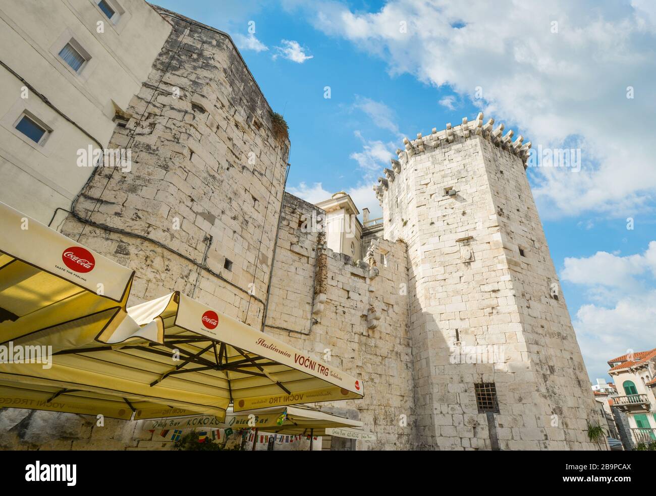 A sidewalk cafe sits under an ancient wall and turret at the Fruit ...